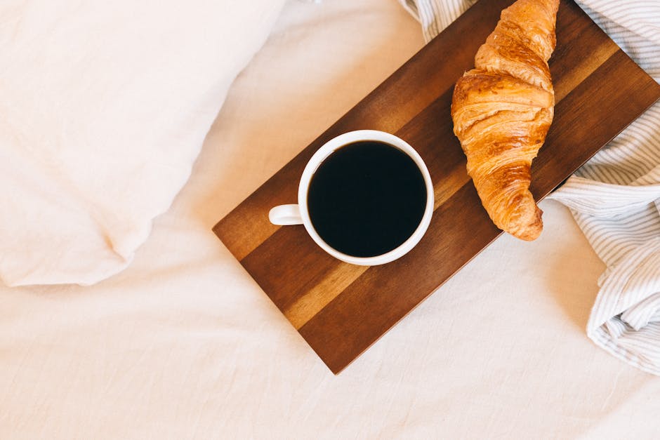 A warm, inviting breakfast of coffee and croissant on a wooden tray, perfect for a cozy morning.